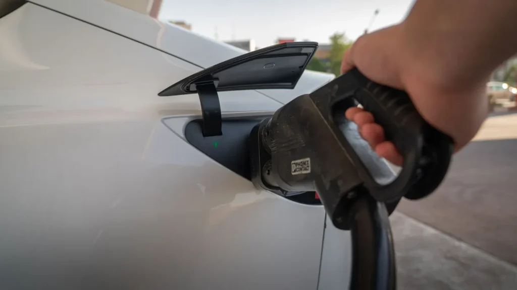 Hand steckt einen Ladestecker in ein weißes Elektroauto
